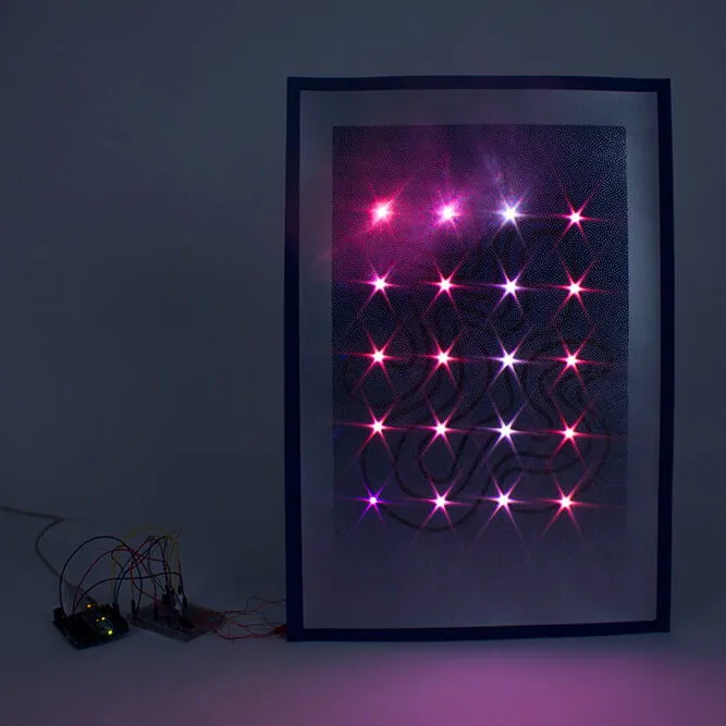 Dans l’obscurité, l’affiche émet de la lumière de différentes nuances de violet. À côté, on voit des leds provenant d’un système électronique.